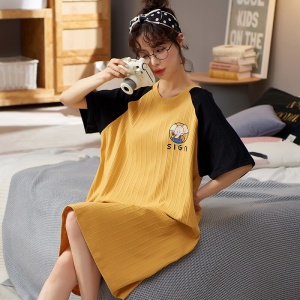 Pijama de verano camisón de manga corta amarillo y negro para mujer llevado por una mujer sentada en una cama en una casa