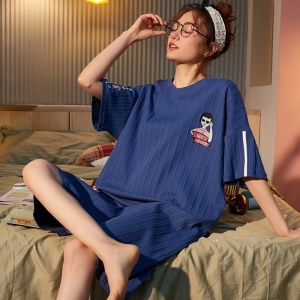 Camisón de algodón azul marino de manga corta que lleva una mujer sentada en la cama de una casa