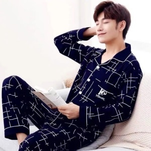 Pijama casual de algodón azul veraniego para hombre sentado en la cama de una casa