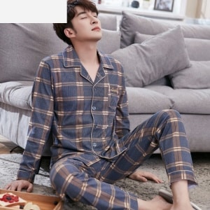 Moderno pijama de algodón a cuadros para hombre llevado por un hombre sentado en la alfombra de una casa