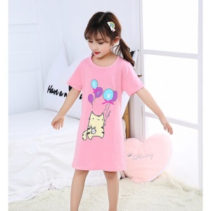 Pijama de algodón con estampado de gatos que lleva una niña en la cama de una casa