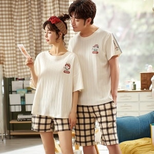 Pijama de camiseta blanco roto y pantalón corto de cuadros de algodón negro y beige que lleva una pareja a la moda en una casa
