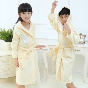 Pijama infantil de conejito de algodón amarillo a la moda, llevado por un niño y una niña en una casa de moda