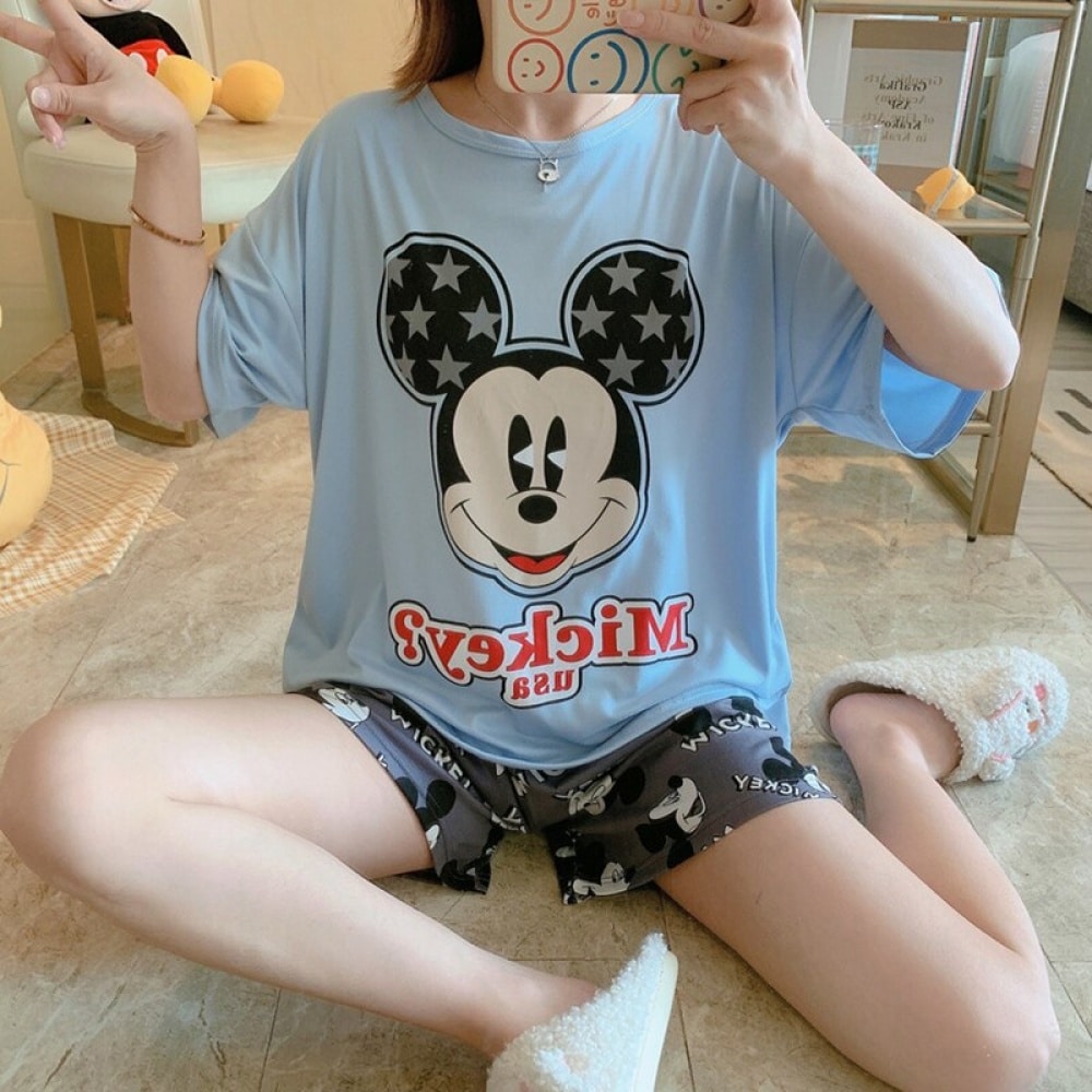 Camiseta azul con motivo de Mickey y pantalones cortos grises, llevados por una mujer sentada en la alfombra de una casa