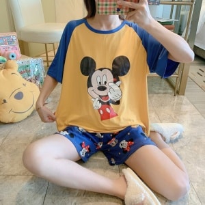 Camiseta de dos piezas y pantalón corto con motivo de Mickey que lleva una mujer sentada que se está haciendo una foto en una casa