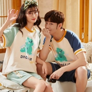 Camiseta de dos piezas de algodón y pantalón corto con motivos de dinosaurios que lleva una pareja sentada en la cama de una casa