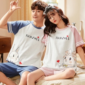 Pijama de dos piezas en camiseta de algodón y pantalón corto con motivo de oso de moda, llevado por una pareja sentada en una cama en una casa
