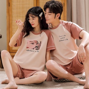 Pijama de dos piezas de algodón con camiseta blanca rosa y pantalón corto rosa que lleva una pareja sentada en la alfombra de una casa