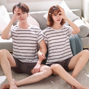 Pijama de dos piezas con camiseta blanca a rayas marrones y pantalón corto marrón, muy de moda, llevado por una pareja en una casa