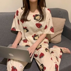 Pijama femenino de dos piezas y manga corta que lleva una mujer sentada en una capanet en una casa