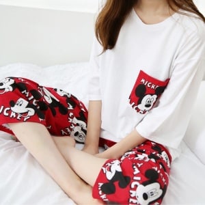 Pijama de dos piezas rojo y blanco con un motivo de Mickey que lleva una mujer sentada en una cama a la moda