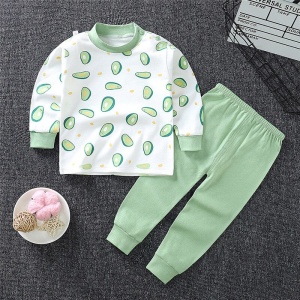 Pijama de niño en algodón aguacate con pantalón verde liso a la moda sobre una alfombra en una casa
