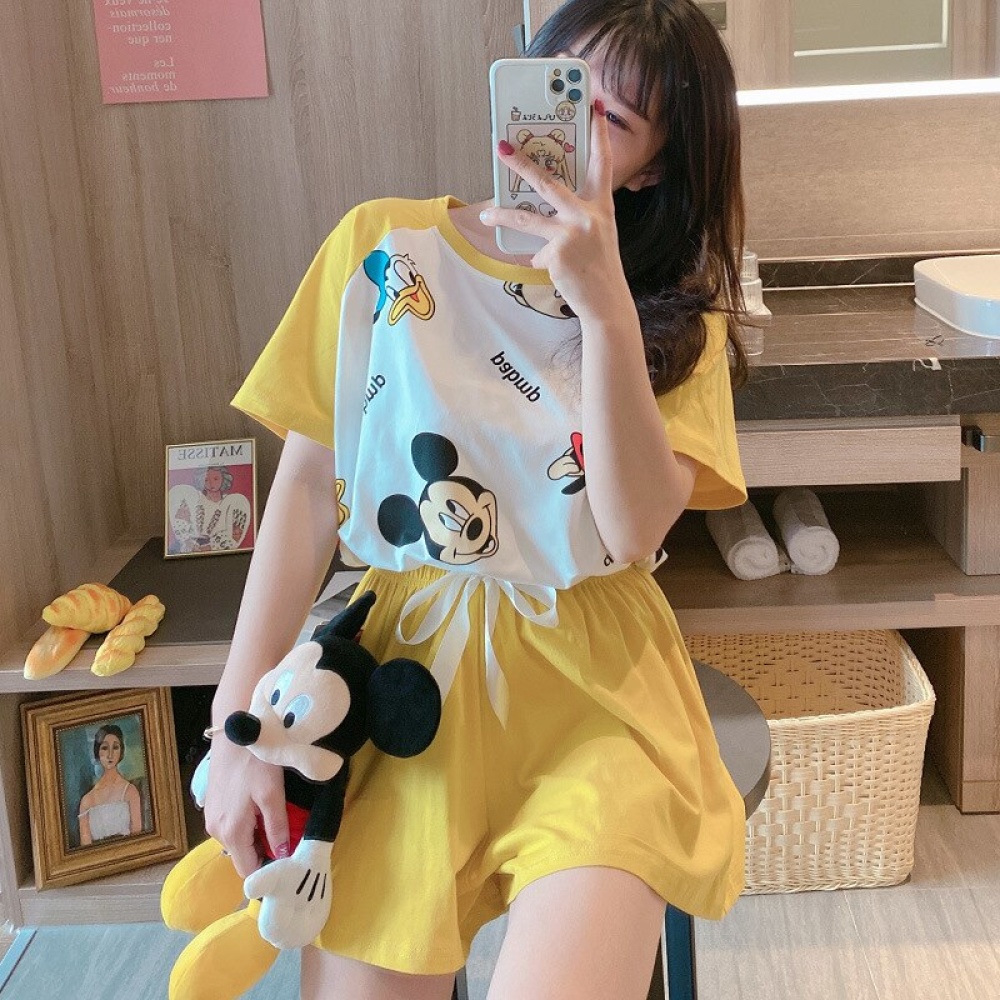 Pijama de verano amarillo con estampado de Mickey Donald que lleva una mujer con un peluche