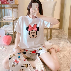Conjunto de pijama de verano de satén estampado de Minnie Mouse que lleva una mujer sentada en la cama de una casa