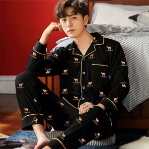 Pijama de camello de algodón que lleva un hombre sentado en una alfombra delante de una cama en una casa