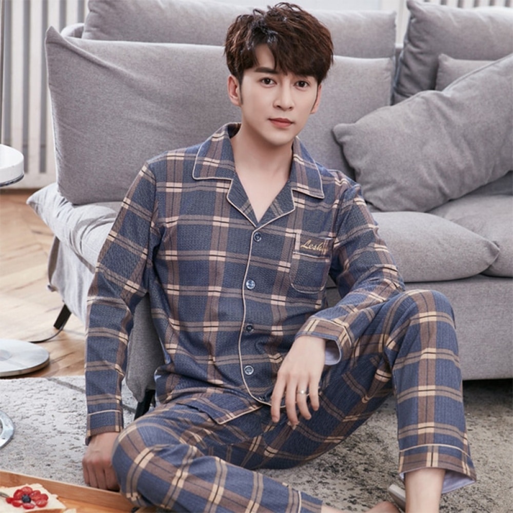Pijama de hombre de cuadros dobles llevado por un hombre sentado en una alfombra delante de un sofá en una casa