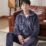 Pijama de franela gris liso para hombre llevado por un hombre delante de un sofá en una casa