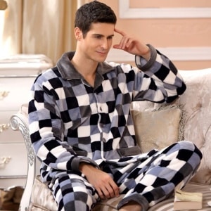 Pijama masculino de forro polar a cuadros llevado por un hombre sentado en el sofá de una casa