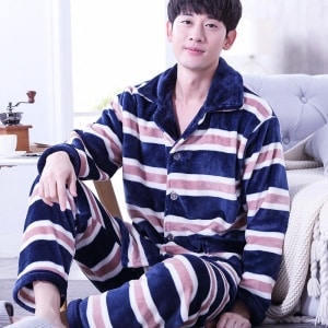 Pijama masculino forrado a rayas llevado por un hombre delante de un sofá en una casa