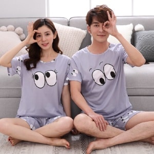 Conjunto de pijama con estampado de ojos que lleva una pareja sentada en la alfombra de una casa