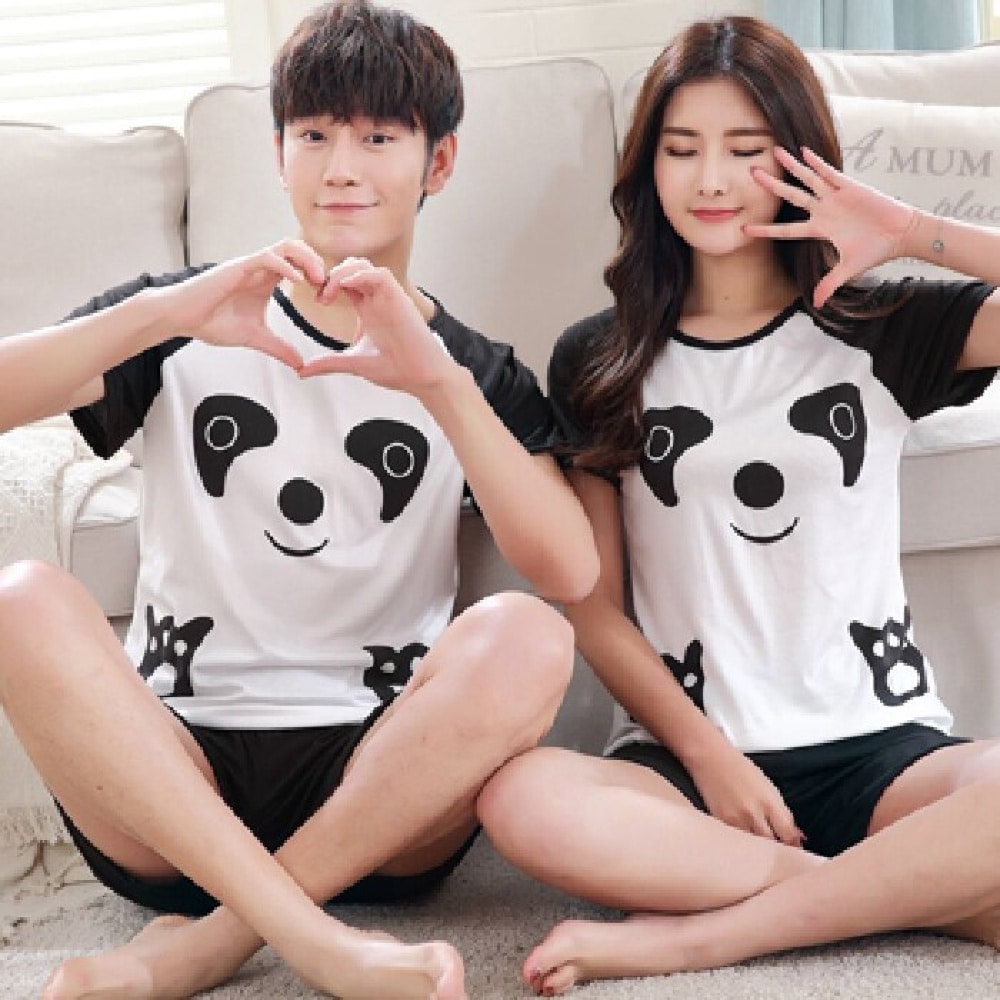 Pijama de panda que lleva una pareja sentada en una alfombra frente al sofá de una casa
