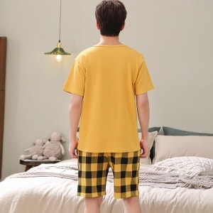 Pijama de verano de manga corta Garfield para hombre en amarillo llevado por un hombre delante de una cama en una casa
