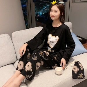 Conjunto de pijama negro con Winnie the Pooh para mujeres a la moda llevado por una mujer sentada en el sofá de una casa