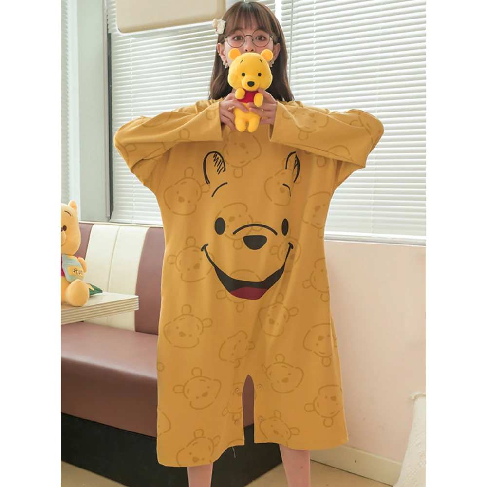 Pijama holgado de mujer amarillo mostaza de Winnie the Pooh que lleva una mujer delante del sofá de una casa
