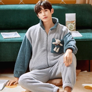 Pijama de invierno con osito de peluche para hombre llevado por un hombre sentado en una alfombra delante de un sofá en una casa