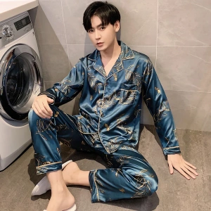 Pijama masculino azul satinado que lleva un hombre sentado delante de una lavadora en una casa