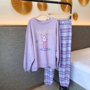 Pijama de cerdito con pantalón a cuadros morados para mujer en una percha en una casa