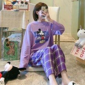 Pijama de Mickey con pantalón a cuadros morados que lleva una mujer haciéndose una foto en una casa