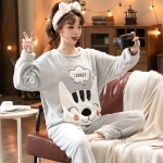 Pijama de pareja de forro polar con cabeza de gato muy cómodo y a la moda que lleva una mujer sentada en una silla en una casa