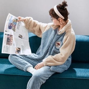 Pijama de pareja de forro polar azul claro que lleva una mujer sentada en el sofá de una casa