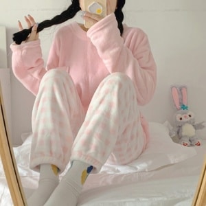 Pijama de invierno suave de mujer en color caramelo y pantalón a rayas rosas y blancas que lleva una mujer haciéndose una foto a la moda