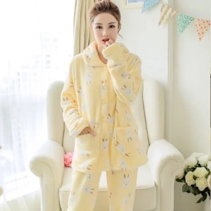 Pijama de invierno con mangas largas y estampado de conejos amarillos, muy cómodo, llevado por una mujer delante de una silla en una casa