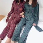 Conjunto de pijama a cuadros de Harry Potter uno verde y otro rojo con dos mujeres llevando el pijama en la cama