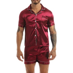Pijama de satén rojo llevado por un hombre con un tatuaje en el brazo izquierdo, el pijama consiste en unos pantalones cortos y una camisa con botones en la parte delantera