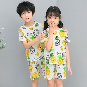 Pijama blanco de dos piezas de piña con dos niños con el pijama puesto y fondo gris