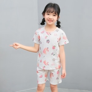 Pijama blanco de dos piezas con dibujo de dibujos animados para niña con una niña vistiendo el pijama y un fondo gris