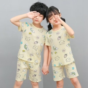 Pijama blanco de dos piezas con dibujo de dibujos animados para niños con dos niños vestidos con el pijama y un fondo gris
