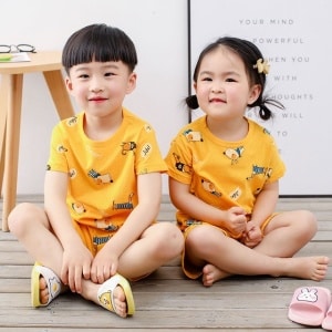 Pijama amarillo de dos piezas con dibujo de dibujos animados para niños con dos niños pequeños vistiendo el pijama