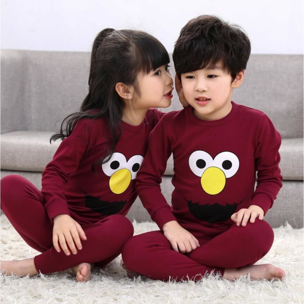 Pijama infantil de dos piezas de primavera con dos niños vestidos con el pijama y un sofá de fondo