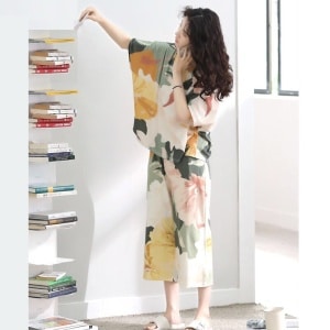 Pijama de verano con manga murciélago y estampado floral que lleva una mujer cogiendo un libro en una casa