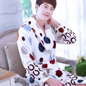Bata de pijama masculina de franela con estampado de lunares multicolores que lleva un hombre sentado en una silla en una casa