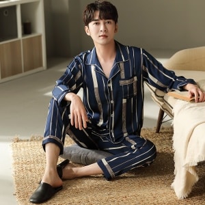 Pijama de algodón a rayas azules con mangas largas que lleva un hombre sentado en una alfombra en una casa