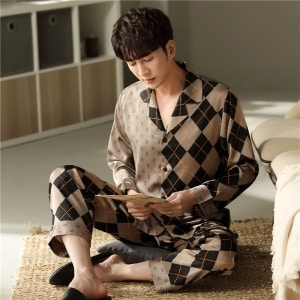 Pijama masculino de algodón de manga larga con cuello doblado llevado por un hombre sentado sobre una alfombra en un dormitorio