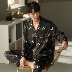 Pijama negro de algodón de manga larga con cuello doblado que lleva un hombre sentado en una silla en una casa