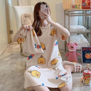 Camisón de pijama con estampado de dibujos animados que lleva una mujer sentada en la alfombra de una casa