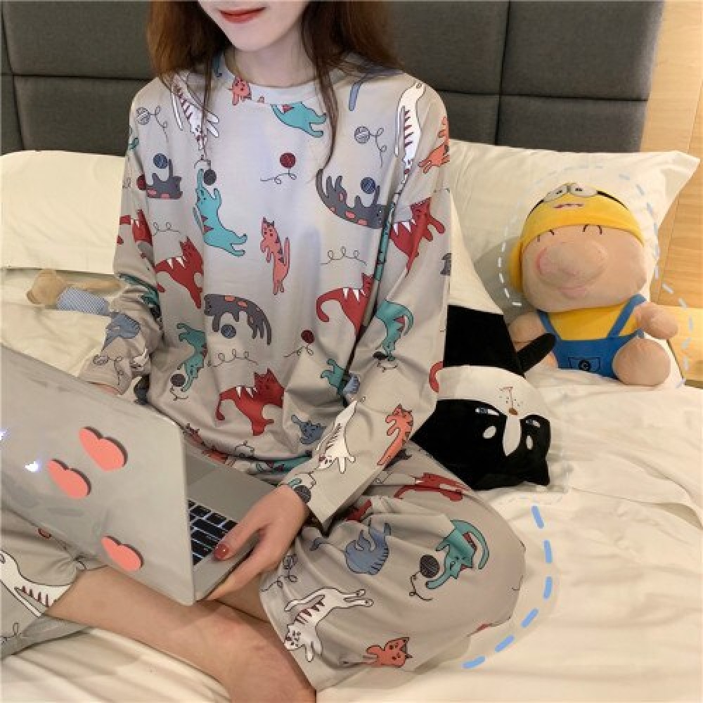 Pijama femenino de manga larga de gato que lleva una mujer sentada en la cama de una casa